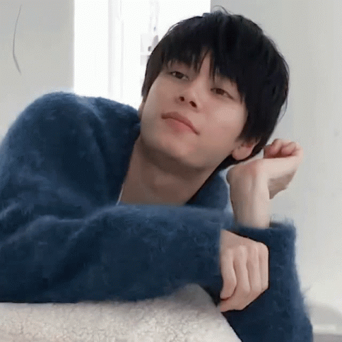 A Young Man In A Blue Sweater Rests His Head On A Pillow GIF