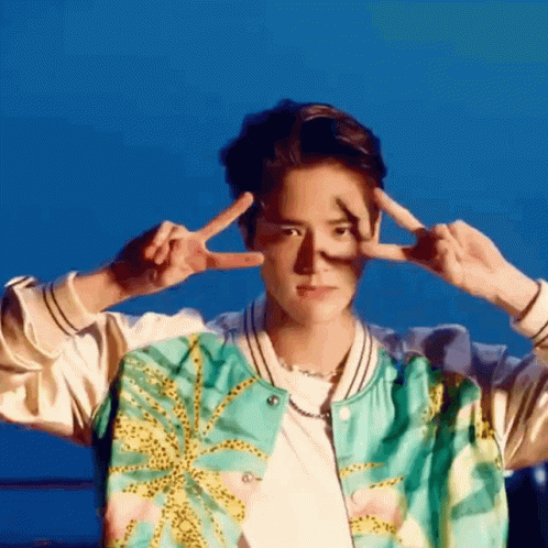 A Young Man In A Bomber Jacket Is Making A Peace Sign With His Hands . GIF