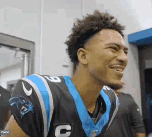 a young man in a carolina panthers uniform is smiling and laughing .