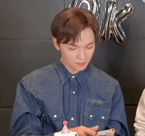 A Young Man In A Denim Shirt Is Holding A Cell Phone . GIF