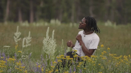 A Young Man In A Field Of Flowers Wearing A Boy Shirt GIF
