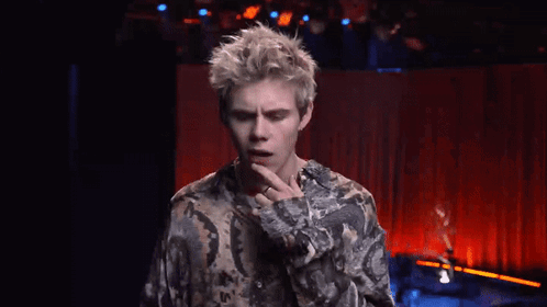A Young Man In A Floral Shirt Is Pointing At Something GIF