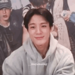 A Young Man In A Gray Hoodie Is Smiling For The Camera . GIF