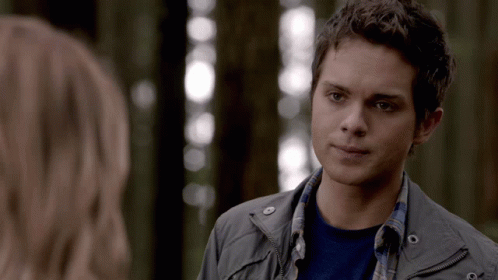 A Young Man In A Gray Jacket Is Looking At A Woman GIF