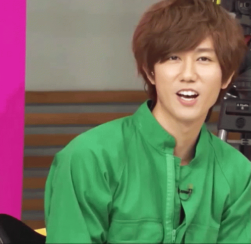 A Young Man In A Green Jacket Is Smiling GIF