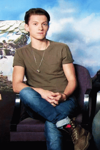 A Young Man In A Green Shirt Sits In A Chair GIF
