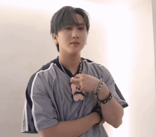 A Young Man In A Grey Shirt Is Holding A Stuffed Animal . GIF