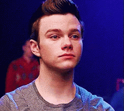 A Young Man In A Grey Shirt Is Looking At The Camera With A Serious Look On His Face . GIF