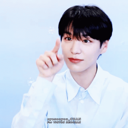 A Young Man In A Light Blue Shirt Is Pointing His Finger Up GIF