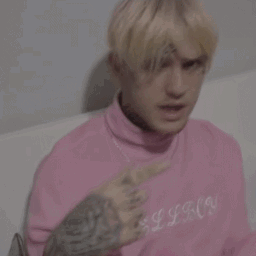 A Young Man In A Pink Sweater Is Making A Heart With His Hands . GIF