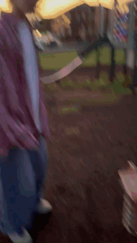 A Young Man In A Plaid Shirt Is Standing In Front Of A Slide In A Park GIF