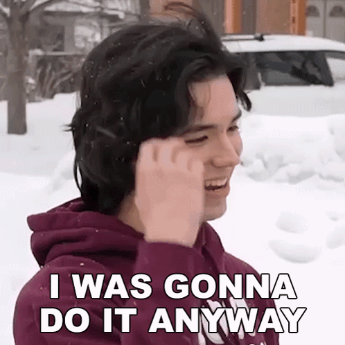 A Young Man In A Purple Hoodie Is Standing In The Snow And Talking On A Cell Phone . GIF