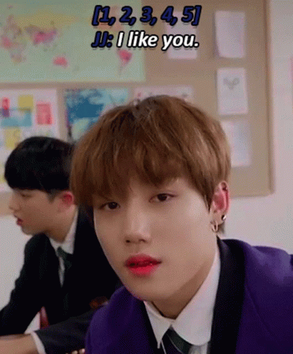 A Young Man In A Purple Suit And Tie Is Sitting At A Desk In A Classroom With Other Students . GIF