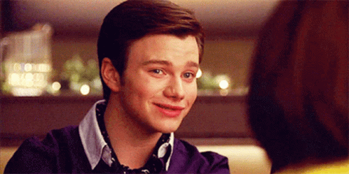 A Young Man In A Purple Sweater Is Smiling GIF