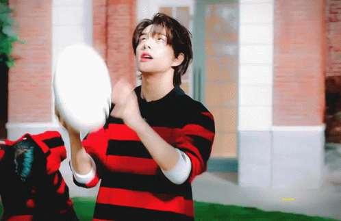 A Young Man In A Red And Black Striped Shirt Is Throwing A Frisbee In The Air . GIF