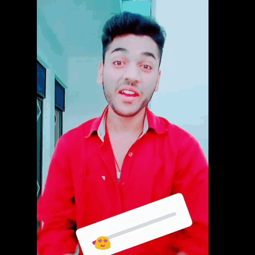 A Young Man In A Red Shirt Is Holding A Sticker With A Yellow Face On It GIF