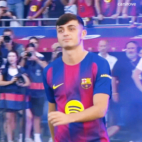 a young man in a soccer jersey is standing in front of a crowd .