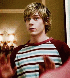 A Young Man In A Striped Shirt Is Standing In A Room With His Hands Outstretched . GIF