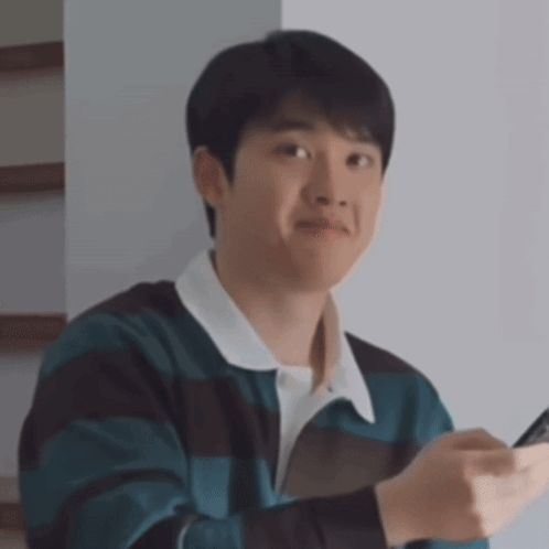 A Young Man In A Striped Sweater Is Holding A Cell Phone In His Hand . GIF