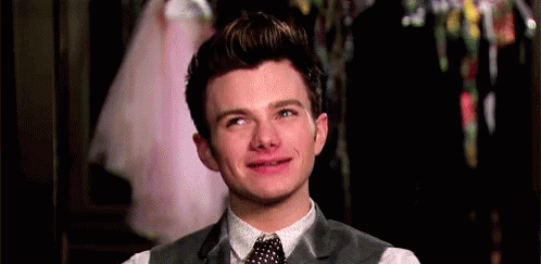 A Young Man In A Suit And Tie Is Smiling And Making A Funny Face . GIF
