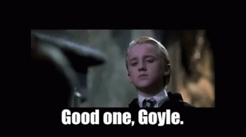 A Young Man In A Suit And Tie Is Standing In A Dark Room . GIF