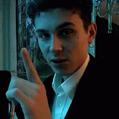 A Young Man In A Suit And White Shirt Is Giving A Thumbs Up Sign GIF