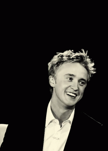 A Young Man In A Suit And White Shirt Is Smiling And Waving GIF