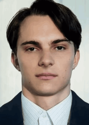 A Young Man In A Suit And White Shirt Looks At The Camera With A Serious Look On His Face GIF