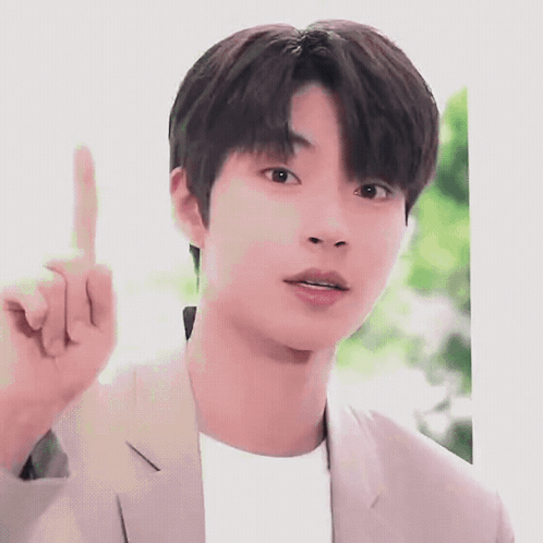 A Young Man In A Suit Is Pointing His Finger Up . GIF