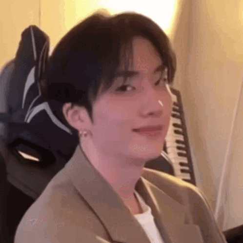 A Young Man In A Suit Is Sitting In A Chair In Front Of A Keyboard . GIF
