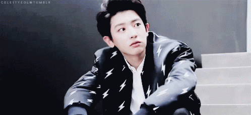 A Young Man In A Suit With Lightning Bolts On It Is Sitting On Stairs . GIF