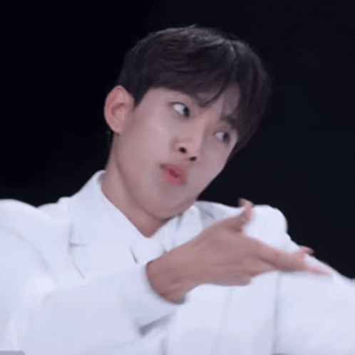 A Young Man In A White Coat Is Making A Funny Face While Pointing At Something . GIF
