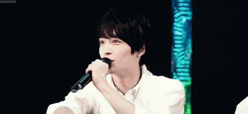 a young man in a white shirt is holding his hand to his forehead .