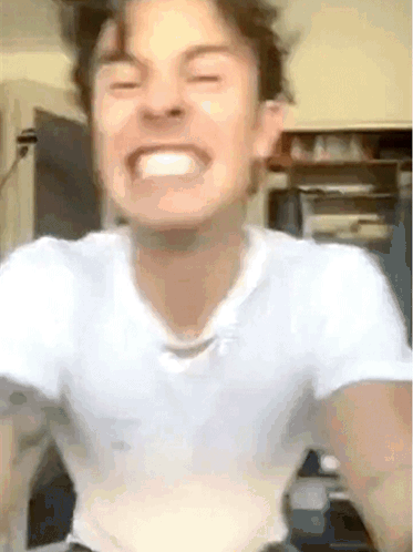 A Young Man In A White Shirt Is Making A Funny Face . GIF
