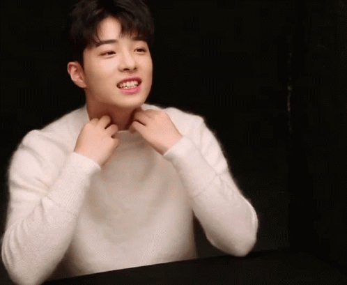 A Young Man In A White Sweater Is Smiling GIF