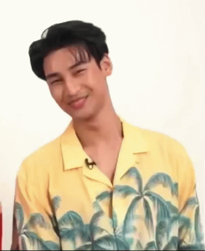 A Young Man In A Yellow Shirt With Palm Trees On It Is Smiling . GIF