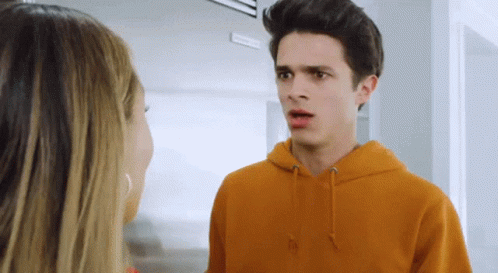 A Young Man In An Orange Hoodie Talks To A Young Woman GIF