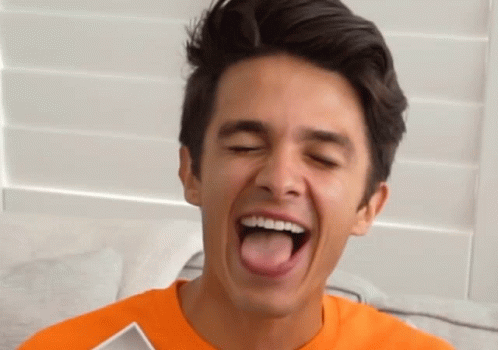 A Young Man In An Orange Shirt Sticks His Tongue Out GIF
