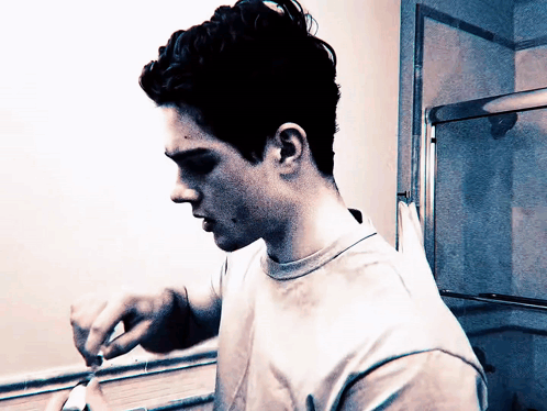 a young man is brushing his teeth in front of a bathroom mirror