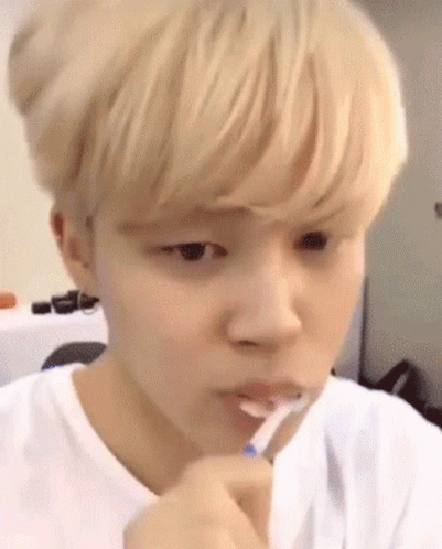 A Young Man Is Brushing His Teeth With A Toothbrush GIF