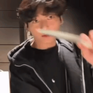 a young man is brushing his teeth with a toothbrush while wearing a black jacket .
