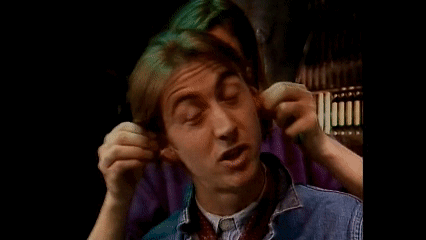 a young man is covering his ears with his hands while making a funny face .