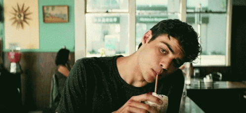 A Young Man Is Drinking A Milkshake Through A Straw . GIF