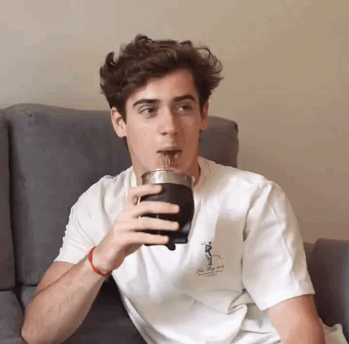 A Young Man Is Drinking From A Cup That Says The Valley Club GIF
