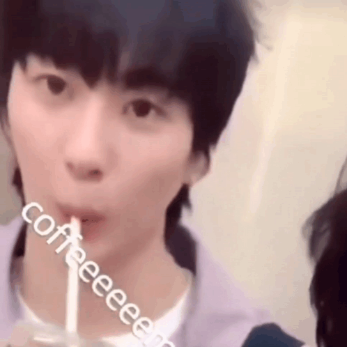 a young man is drinking from a cup with a straw .