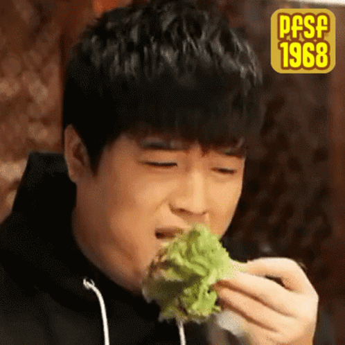 A Young Man Is Eating A Piece Of Lettuce With The Year 1968 On The Bottom Right GIF