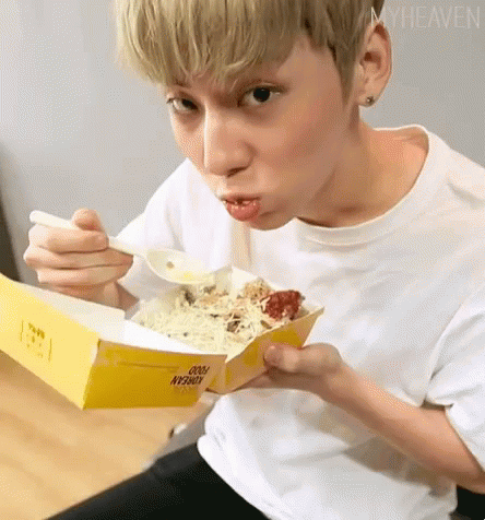 A Young Man Is Eating Food From A Box With A Spoon And Making A Funny Face . GIF