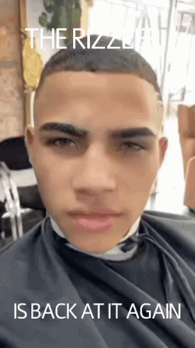 A Young Man Is Getting His Hair Cut At A Barber Shop With The Caption " The Rizzla Is Back At It Again " GIF