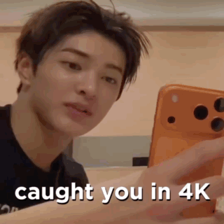 A Young Man Is Holding A Cell Phone In His Hand . GIF