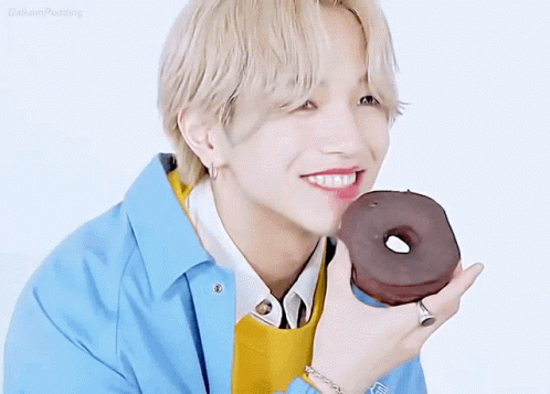 A Young Man Is Holding A Chocolate Donut In His Hand . GIF